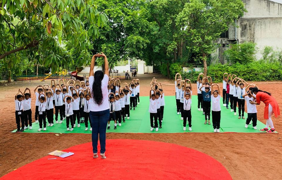 Students practising yoga on the school ground with a teacher leading