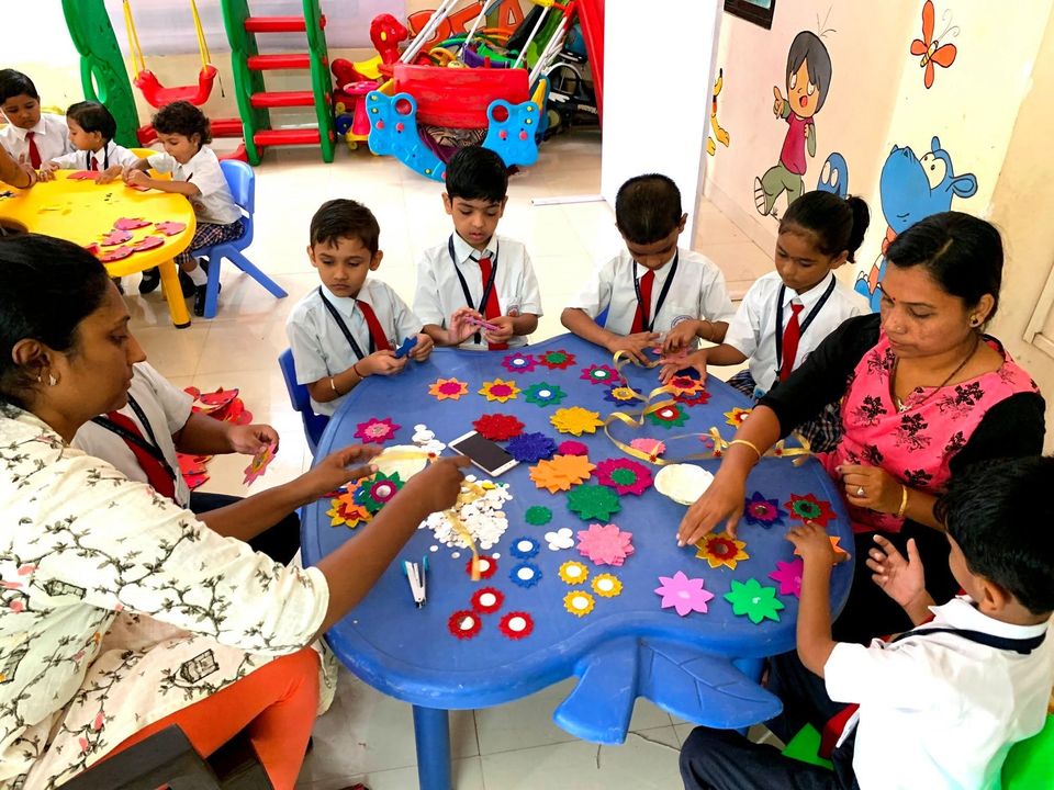 A teacher and children making paper flowers at a classroom table