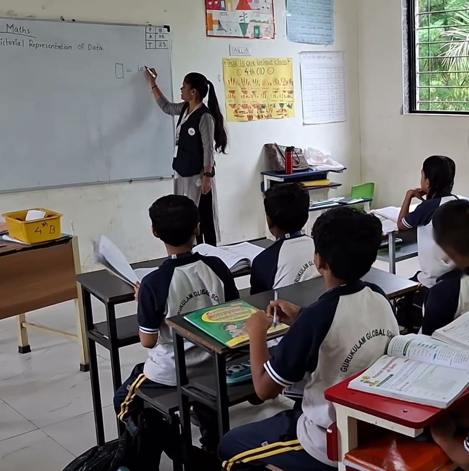 A teacher explains a maths lesson at the whiteboard to a middle-school class