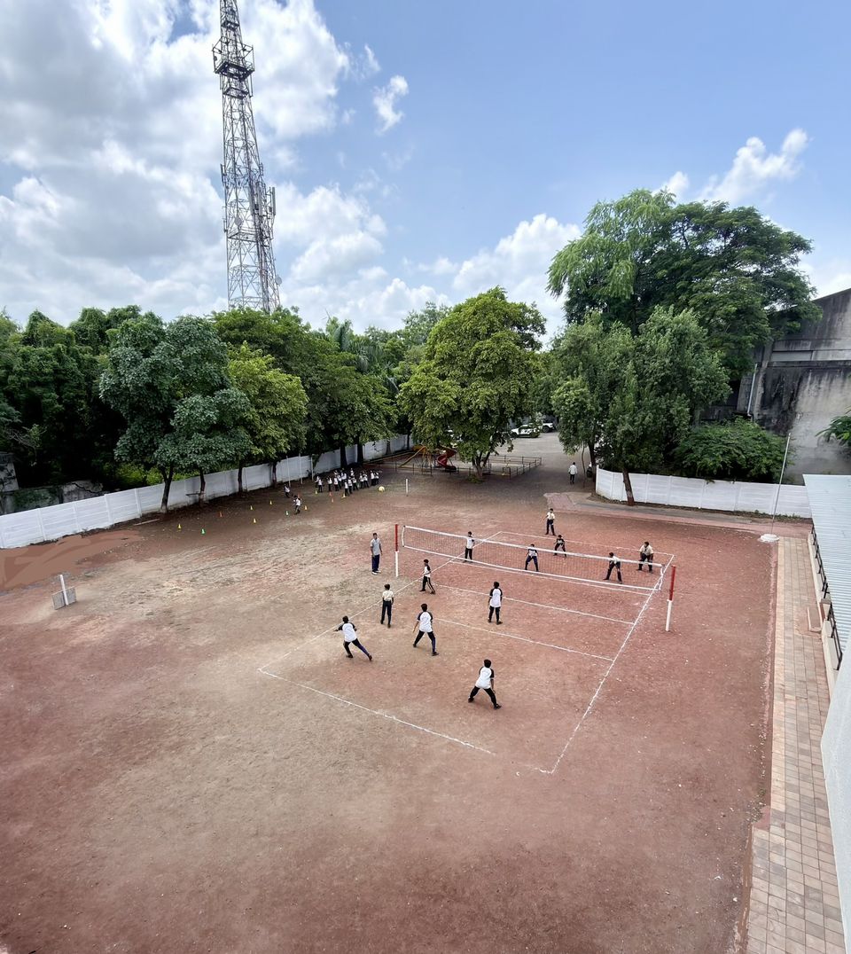 The school ground under the trees, with a volleyball match in progress