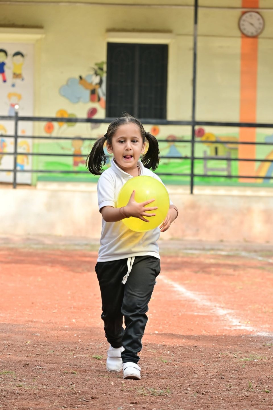 A nursery child with her ball on the track